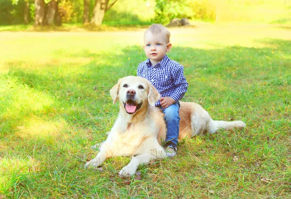 Petit garçon enfant assis sur Golden Retriever chien sur l'herbe — Photo