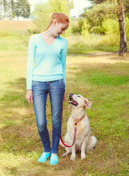 Gelukkige eigenaar vrouw en Golden Retriever hond wandelen in het park — Stockfoto