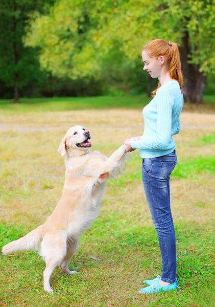 Glückliche Besitzerin spielt mit Golden Retriever Hund auf Gras in — Stockfoto