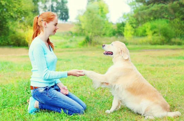 Happy owner woman training Golden Retriever dog on grass in park — Stock Photo, Image