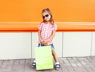 Alışveriş torbaları şehirde yürüyüş ile bir güneş gözlüğü takmış çocuk