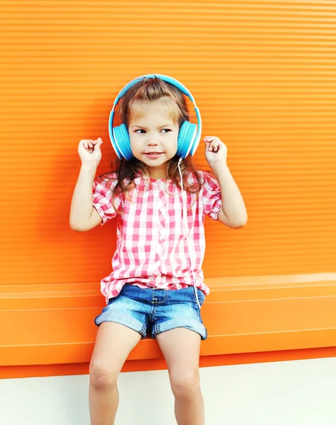 Vackra leende barn lyssnar på musik i hörlurar över colo — Stockfoto