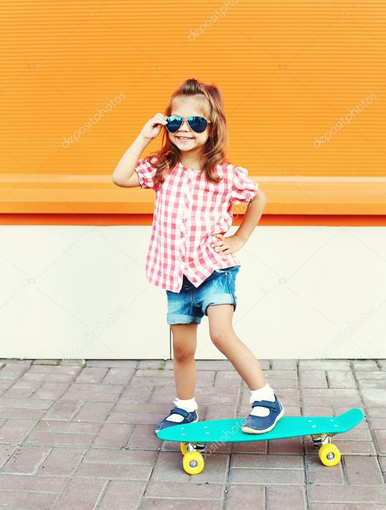 Fashion kid - smiling stylish little girl child with skateboard 