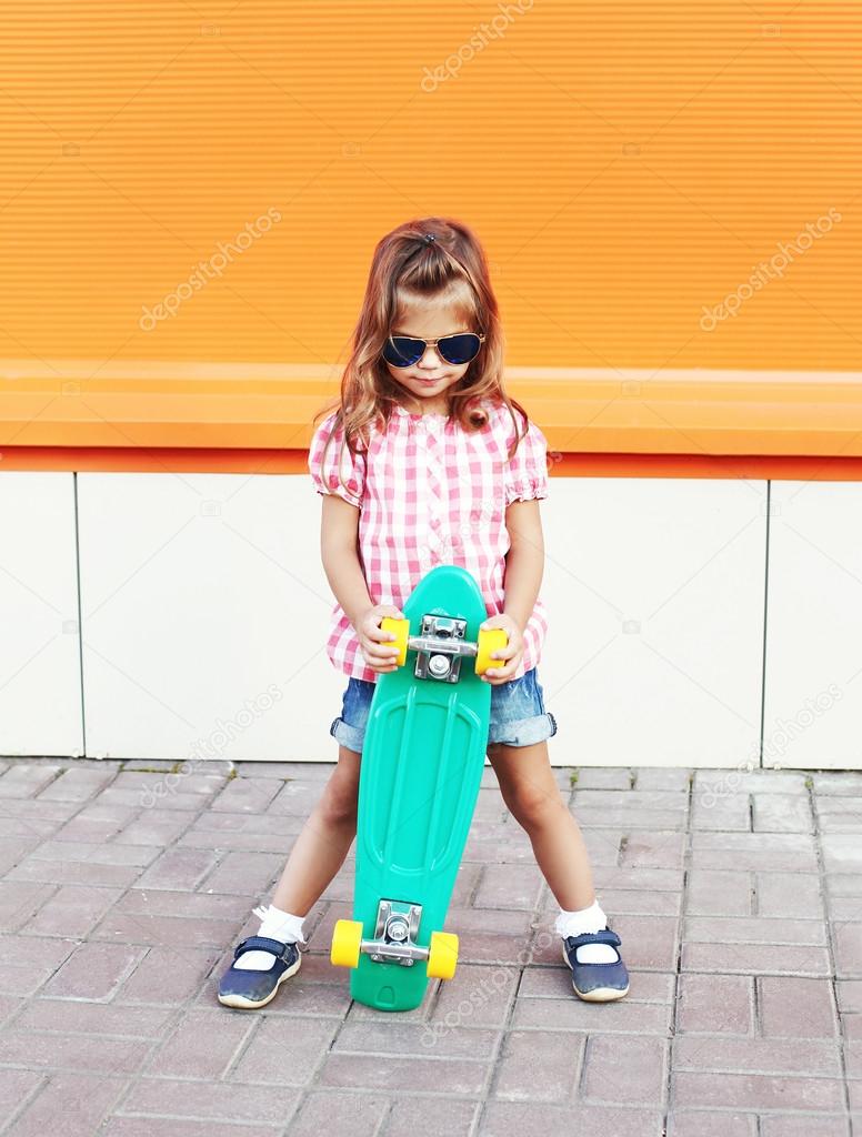 Fashion little girl child with skateboard wearing a sunglasses a