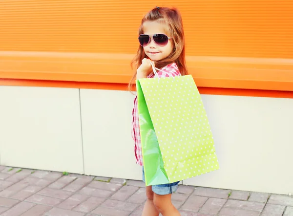Felice bambino indossa un occhiali da sole con borse della spesa a piedi in c — Foto Stock