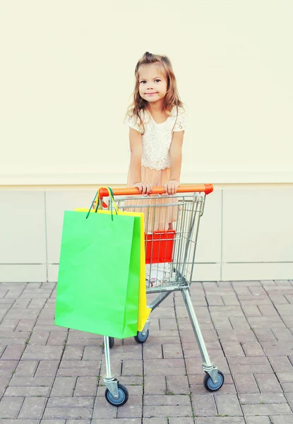 Feliz sorrindo menina criança sentada no carrinho de carrinho com col — Fotografia de Stock