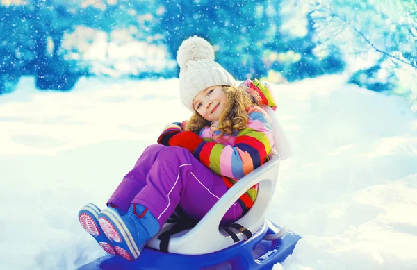 Lächelndes kleines Kind sitzt im Wintertag auf Schlitten — Stockfoto