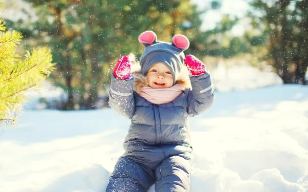 Веселый милый маленький ребенок играет на снегу в зимний день — стоковое фото