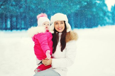 Mutlu anne ve çocuk karlı kış ormanda yürüyüş