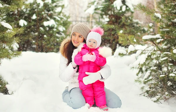 Mooie moeder met kind in besneeuwde winterdag op sneeuw — Stockfoto