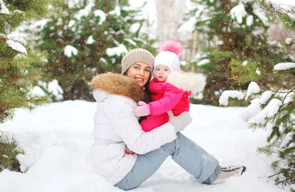 Bonne mère souriante avec enfant dans une journée d'hiver enneigée sur la neige — Photo