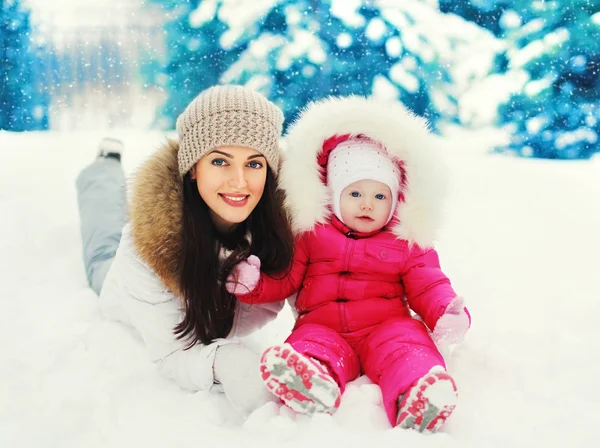 Happy leende mor och barn på snö i snöig vinterdag — Stockfoto