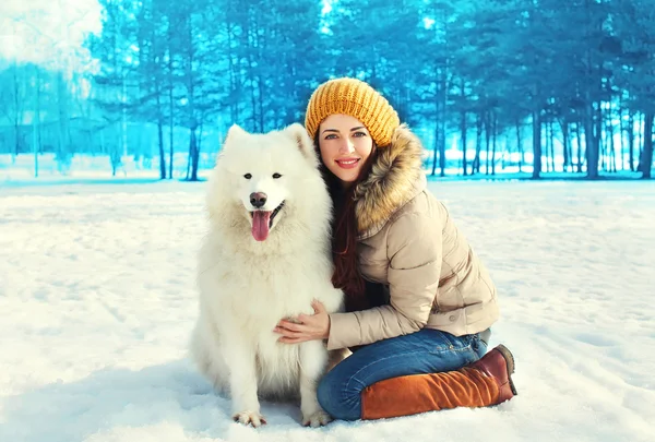 Szczęśliwy uśmiechający się właściciel kobieta i biały pies Samoyed w winter park — Zdjęcie stockowe