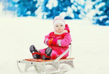 Şirin çocuk kızak ile kar kış günü içinde oturuyor.