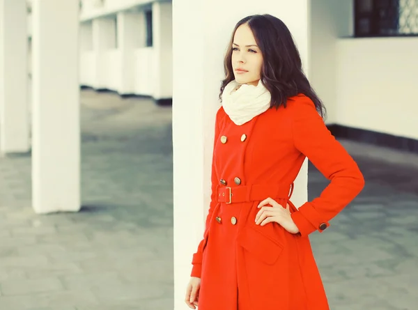 Beautiful young woman wearing a red coat and scarf in city — Stock Photo, Image