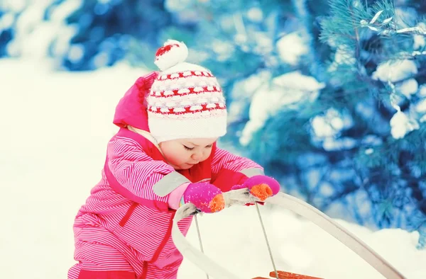 सुंदर छोटा बच्चा सर्दियों के दिन बर्फ पर स्लेड के साथ खेल रहा है — स्टॉक फ़ोटो, इमेज
