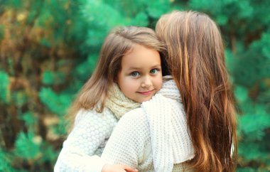 Happy little girl child hugging mother in winter day