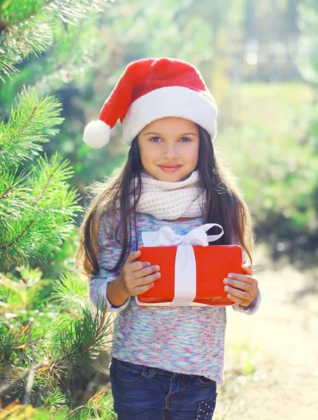 Christmas little girl child in santa red hat with gift box — Stockfoto