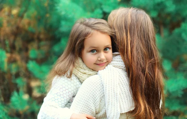 Happy little girl child hugging mother in winter day — Zdjęcie stockowe