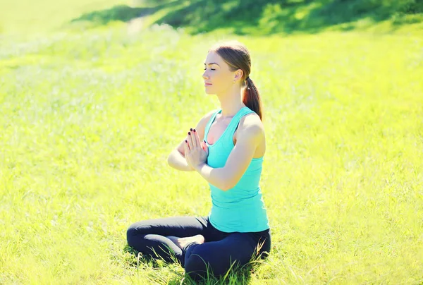 Yoga girl meditates sitting on grass in sunny summer day, view p — Stockfoto