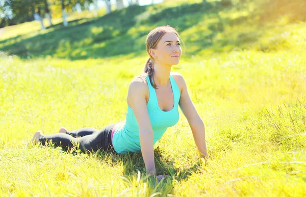 Jeune femme faisant des exercices de yoga sur l'herbe en journée d'été — Photo