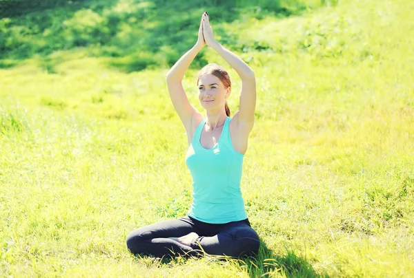 Young woman doing yoga exercises sitting on grass in sunny summe — Stock Photo, Image