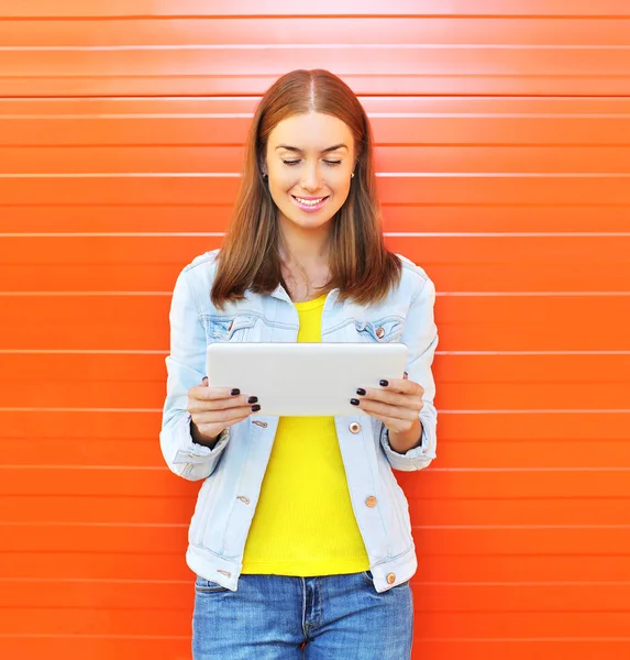 Happy smiling woman using tablet pc computer in city over orange — Stock Photo, Image