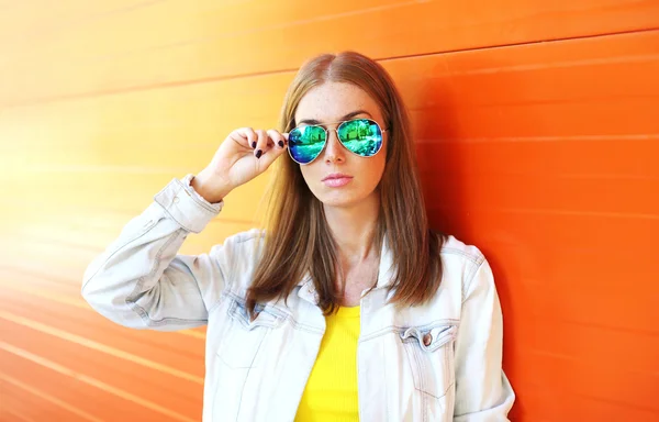 Portrait belle femme en lunettes de soleil sur fond orange coloré — Photo