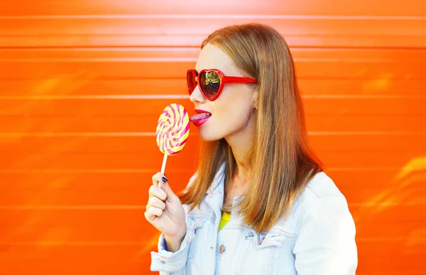 Portrait young woman with sweet caramel lollipop over colorful o — Stok Foto