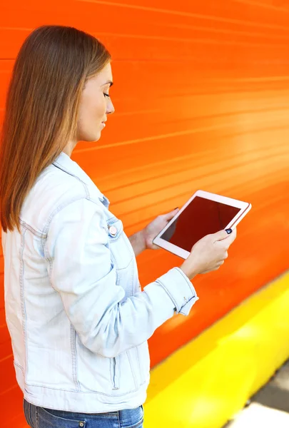 Женщина с планшетного компьютера в профиль на оранжевом фоне — стоковое фото