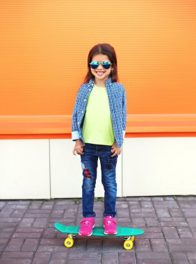 Happy cheerful smiling stylish little girl child with skateboard