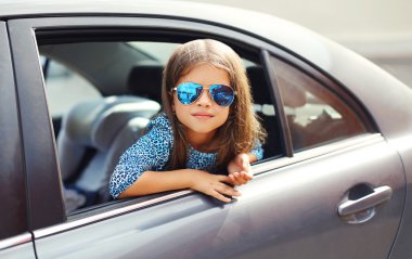 Portrait of beautiful little girl child sitting in car, looking 