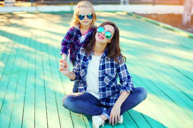Fashion young mother and child daughter wearing a sunglasses and