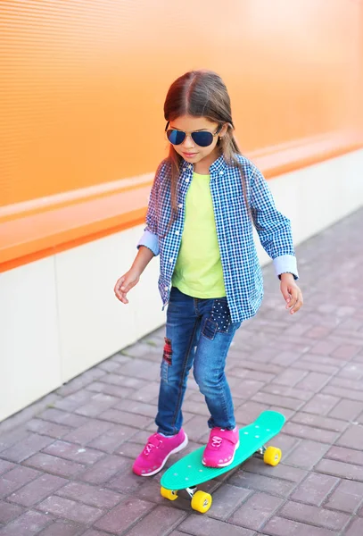 Moda criança no skate usando um óculos de sol e xadrez s — Fotografia de Stock