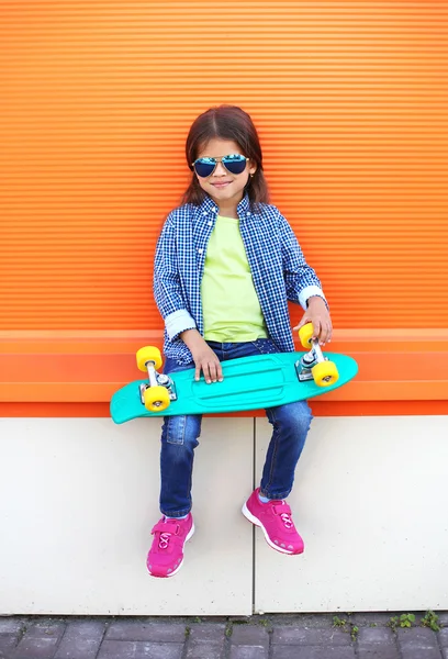 Fashion kid with skateboard wearing a sunglasses and checkered s — Stock Photo, Image