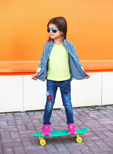 Fashion kid with skateboard wearing a sunglasses and checkered s — Stock Photo, Image