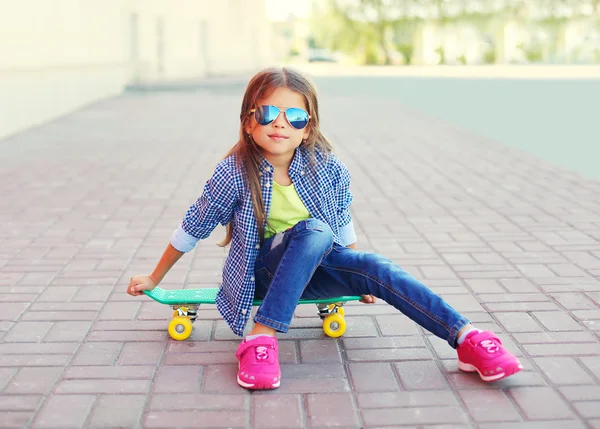 Mode kleines Mädchen Kind sitzt auf Skateboard in der Stadt, trägt — Stockfoto