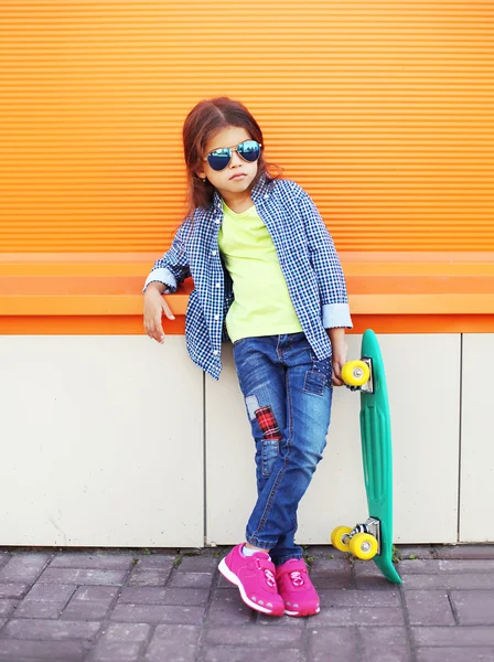 Moda menina criança com skate usando um óculos de sol um — Fotografia de Stock