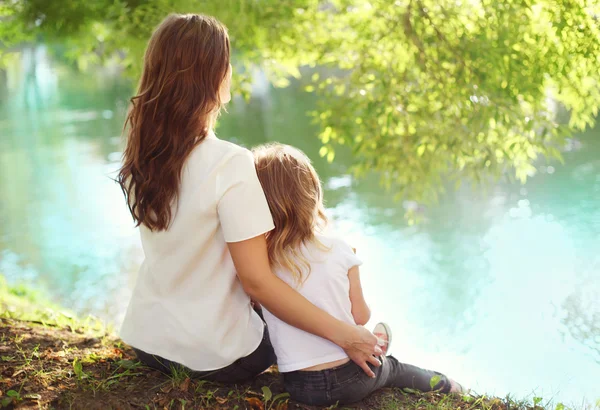 Lycklig mor och barn dotter sitter tillsammans i sommardag — Stockfoto