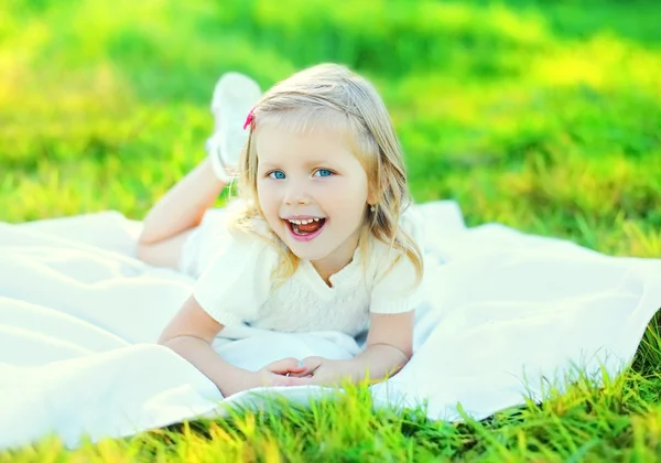 Feliz niña sonriente acostada en la hierba en el soleado verano d —  Fotos de Stock