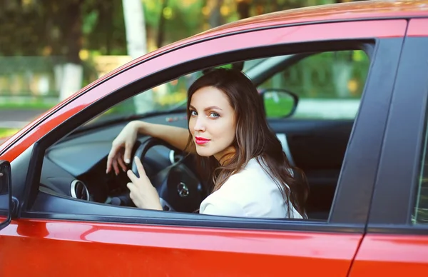 Giovane bella donna conducente al volante auto rossa — Foto Stock
