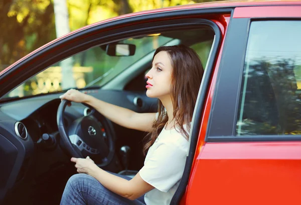 Fiatal nő a vezető mögött a kerék piros autó profil — Stock Fotó