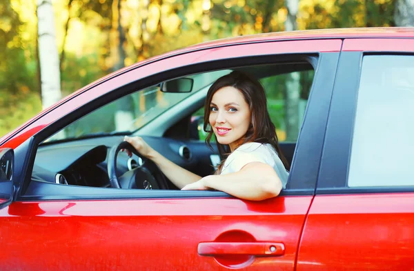 Портрет улыбающейся женщины-водителя за рулем красной машины — стоковое фото