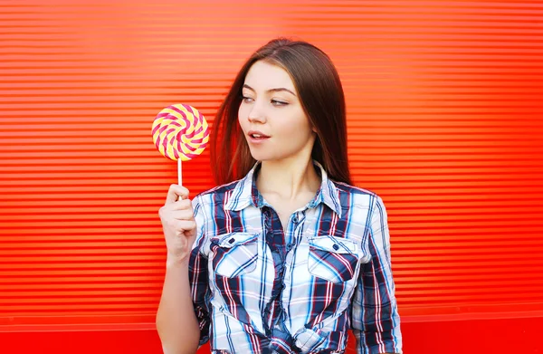 Porträt Mädchen mit süßem Karamell-Lutscher auf rotem Hintergrund — Stockfoto