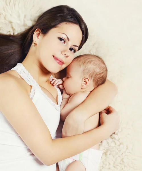 Портрет счастливой молодой матери, спящей с младенцем на кровати дома, т — стоковое фото