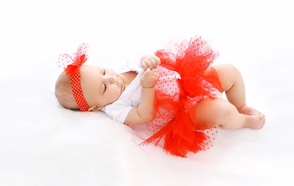 Hermosa niña bebé en falda roja acostado en la cama —  Fotos de Stock