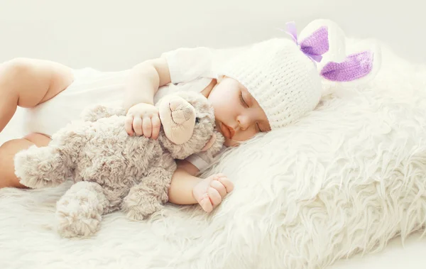 Lindo bebé durmiendo con osito de peluche juguete en blanco suave cama en casa —  Fotos de Stock