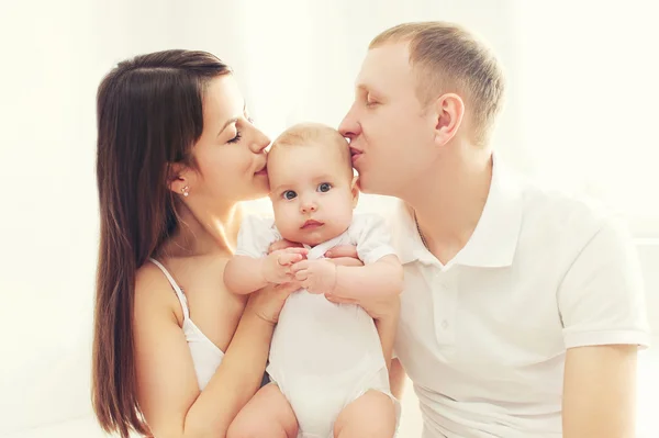 Boldog család, anya és apa csókolózás baba fehér szobában — Stock Fotó