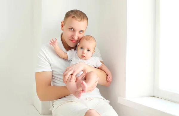 Boldog fiatal apa, és a baba otthon fehér szobában közelében ablak — Stock Fotó