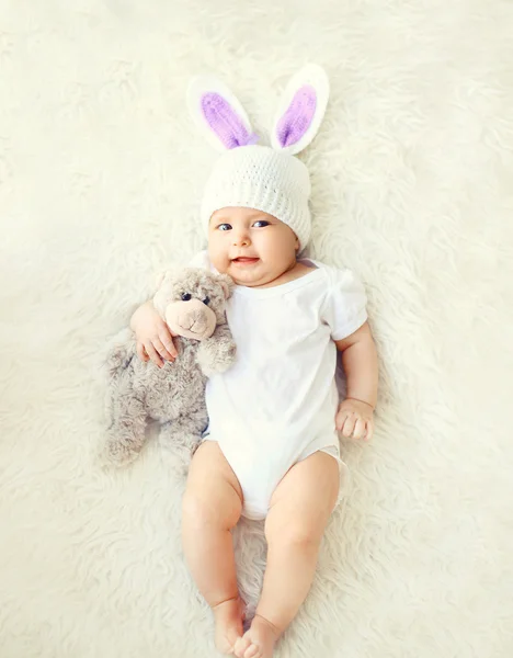 Feliz bebé dulce en sombrero de punto con orejas de conejo y teddy bea —  Fotos de Stock